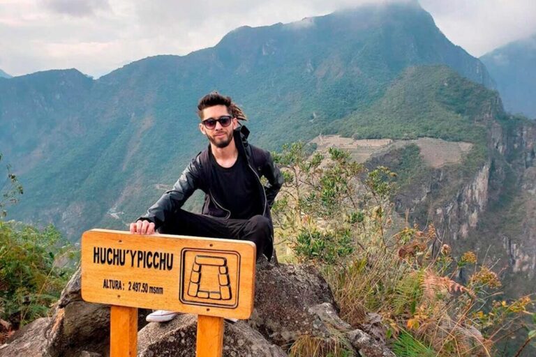 Tourist at the Huchuy Picchu viewpoint overlooking Machu Picchu in Peru.