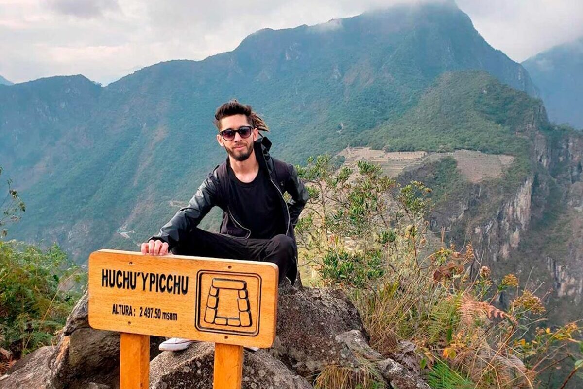 Tourist at the Huchuy Picchu viewpoint overlooking Machu Picchu in Peru.