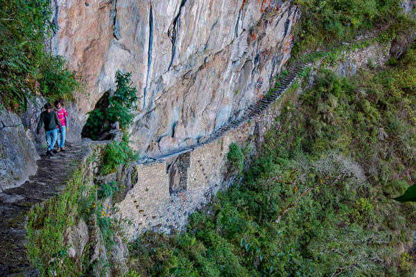 Tourists walking along the Inca Bridge route at Machu Picchu, Peru.