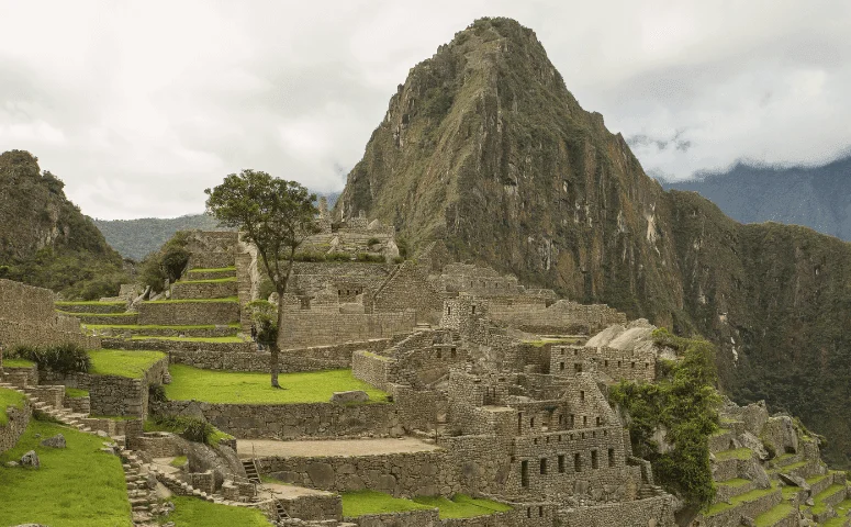 Stone ruins and terraces of Machu Picchu with Huayna Picchu mountain behind.